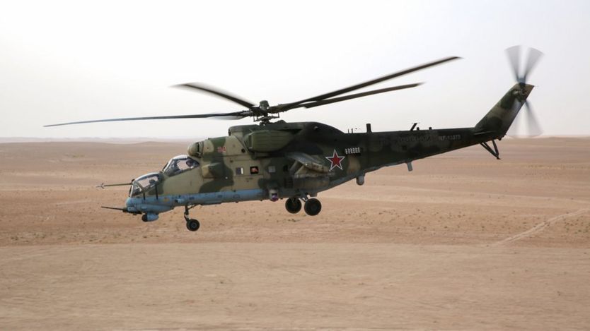A Russian Mil Mi-24 'Hind' attack helicopter flying in the eastern Syrian region of Deir Ezzor. The landscape is an open desert.