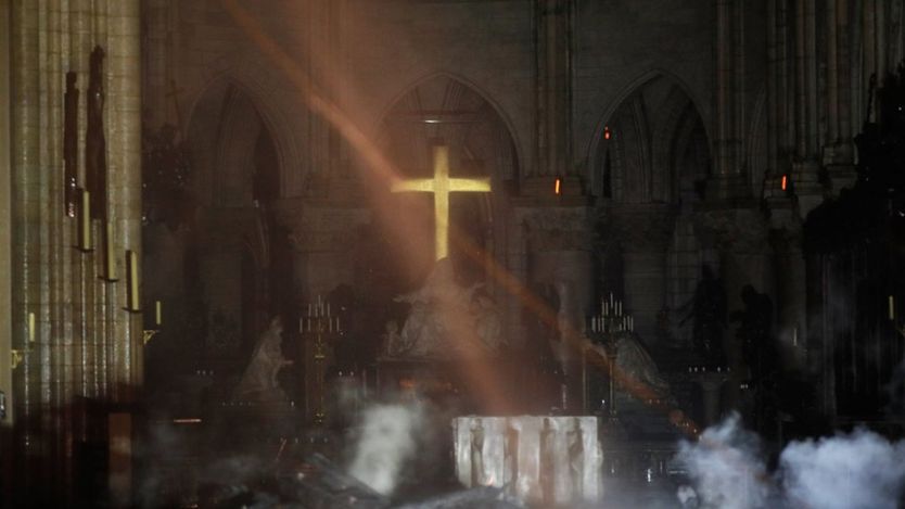 Smoke rises around the alter in front of the cross inside the Notre Dame Cathedral as a fire continues to burn in Paris, France, April 16, 2019.