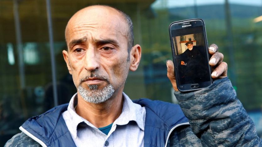 عمر نبی در حالی که عکس پدرش داود نبی را بروی گوشی تلفن همراهش نشان میدهد در برابر خبرنگاران حاضر شده است