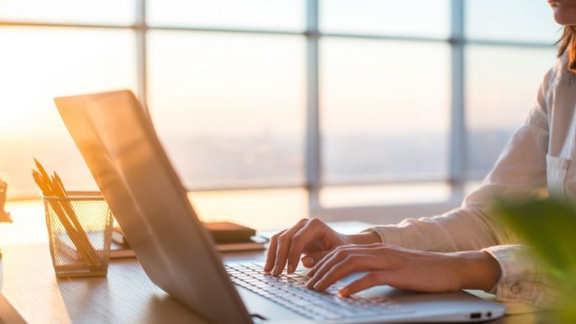 Una mujer escribe en computadora.