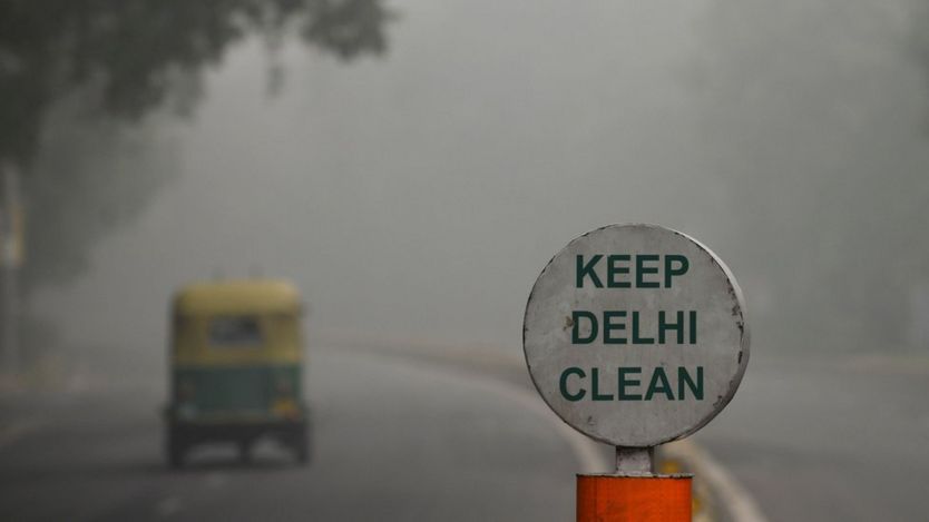 A sign reading "Keep Delhi clean" with a thick smog in the background