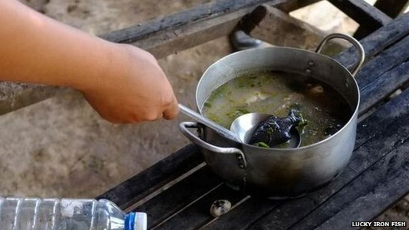 An iron fish being stirred into soup in Cambodia