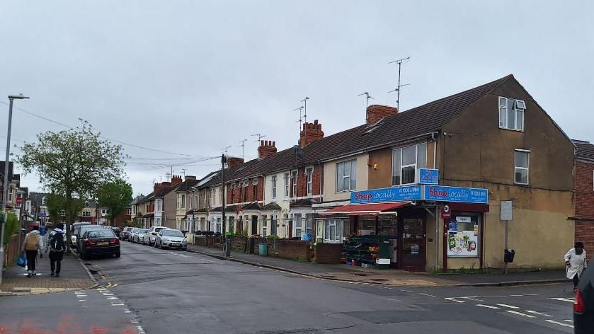 An image of the Shop Locally off license at the end of a row of terraced houses on Broad Street, Swindon.