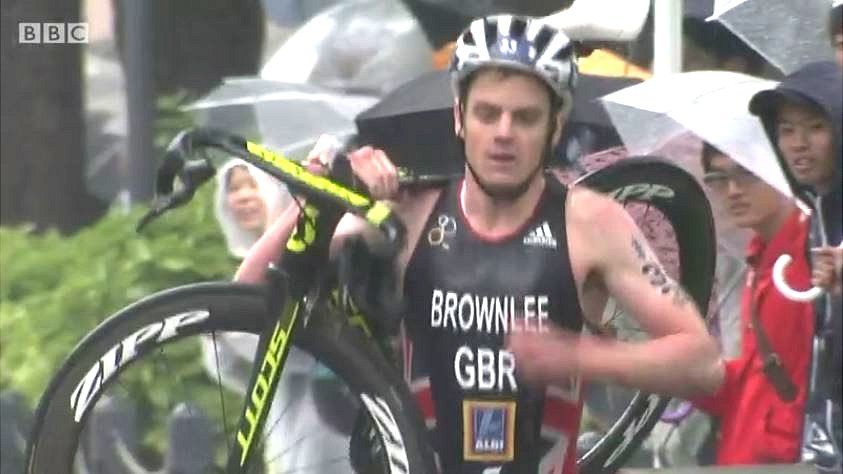 Jonny Brownlee carries his bike after crashing in a triathlon in Japan