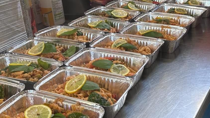 Rows of aluminium takeaway food trays containing identical meals