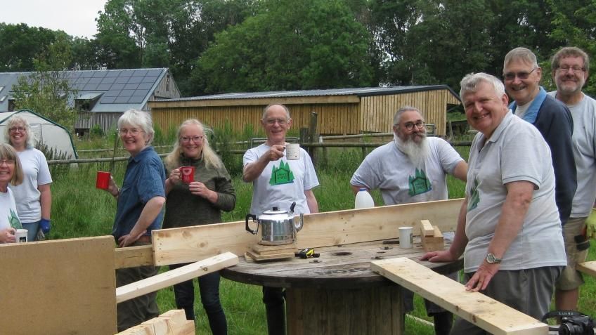 A group of people standing around a woodworking table