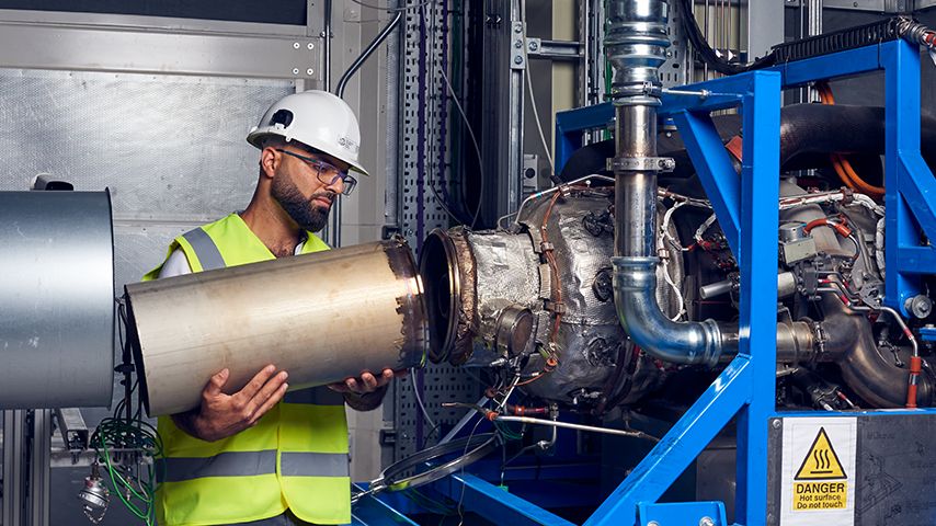 Ihab Amed working on the test jet engine. He's connecting a metal tube to another piece of equipment.