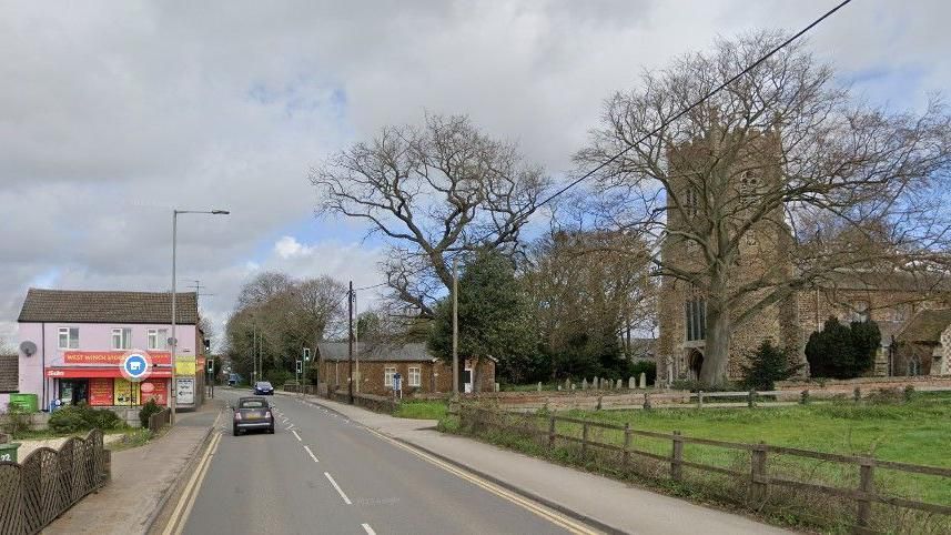 A10 in West Winch with a store on one side of road and church on other