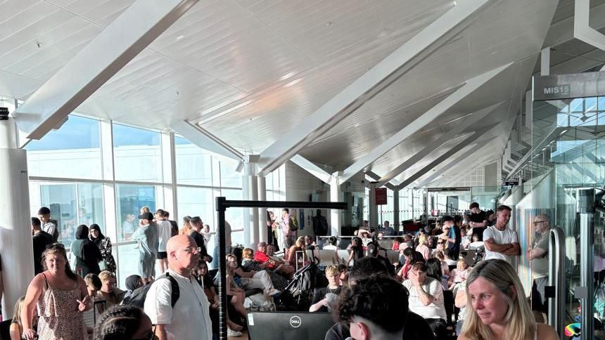 Dozens of passengers waiting at a boarding gate