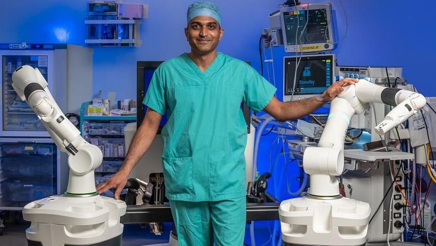 A surgeon between two robotic arms