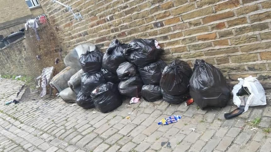 Fly-tipped bags in an alleyway