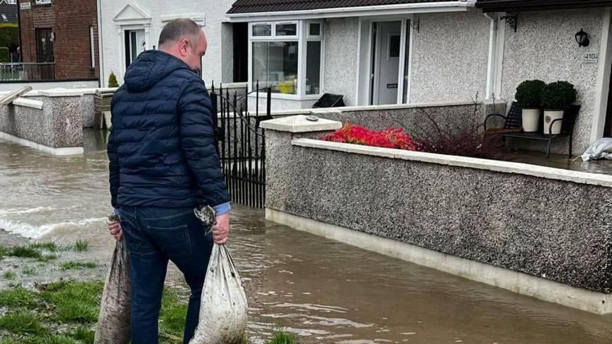 sandbags being carried to flooded homes in derry