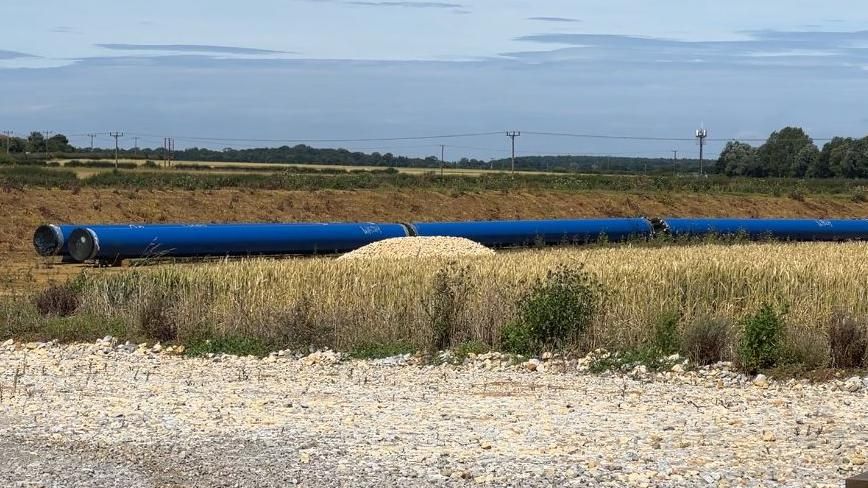 Sections of blue plastic pipe in a barren field