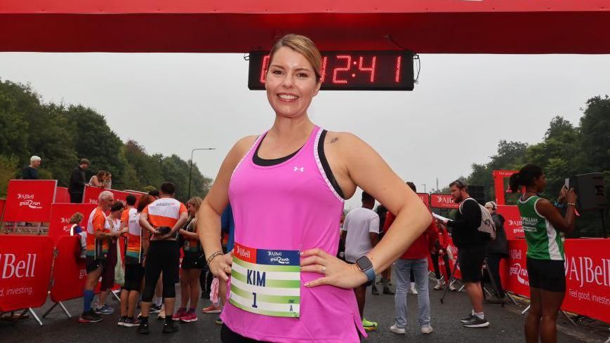 North East Mayor Kim McGuinness at the start line smiling with her hands on her hips. She is wearing a pink top and her hair is tied back.