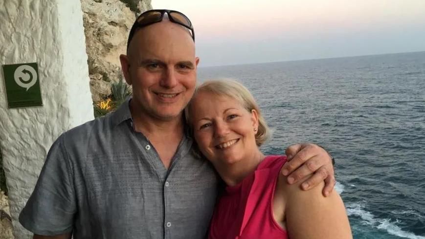 Man and woman cuddling near sea during sunset. 