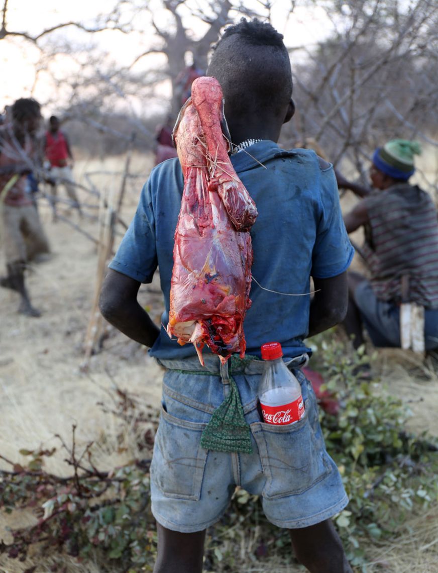 Hadza cargando carne y una botella de Cocacola