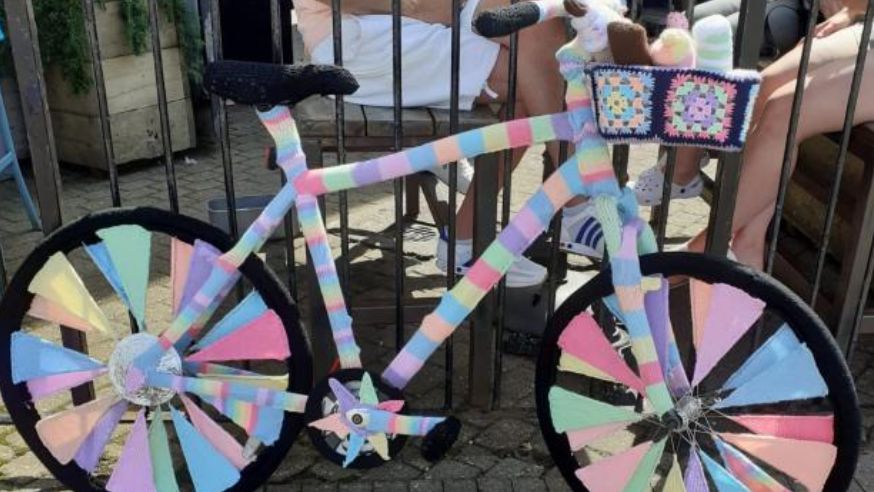 Knitted ice cream bike with basket made of pink, blue, green, black and orange yarn