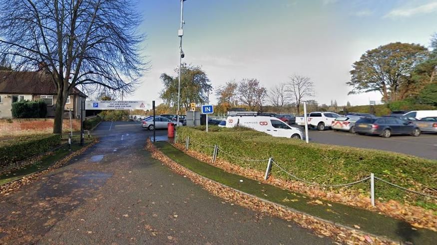 Car park with height restrictor over entrance, IN sign and parked vehicles