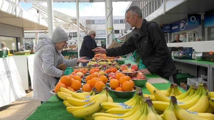 A woman pays for fruit at a stall in Yate town centre