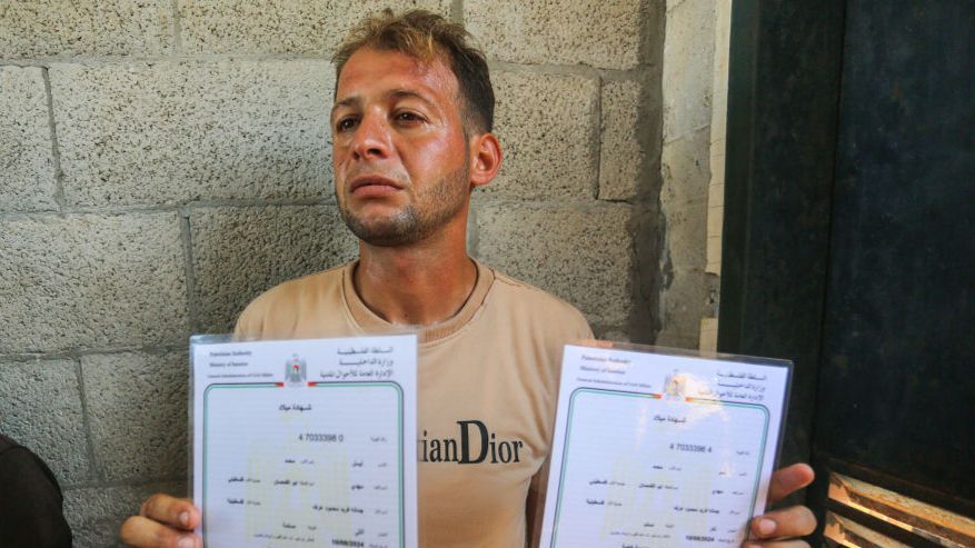 Palestinian father Mohammed Abu al-Qumsan holding the birth certificates of his twins