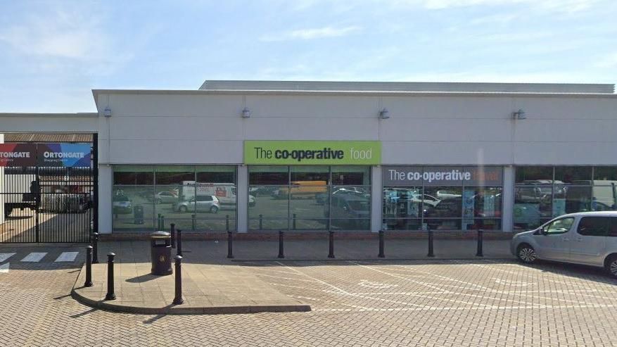 Co-op store in glass and steel building with large car park in front