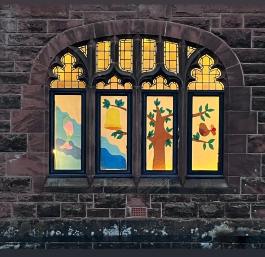 An arched window with a pane each for a fish, bell, tree and bird