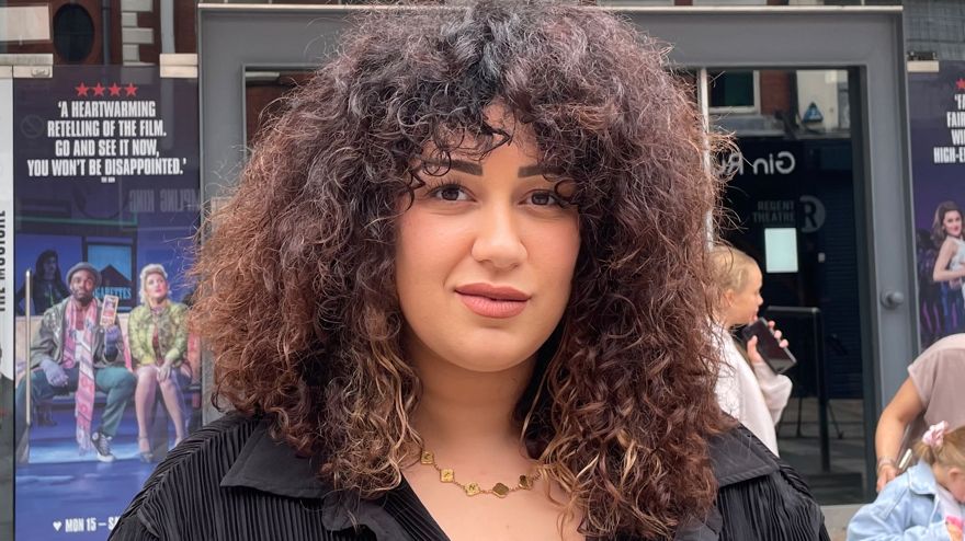 A woman with dark curly hair and black blouse stood outside a theatre