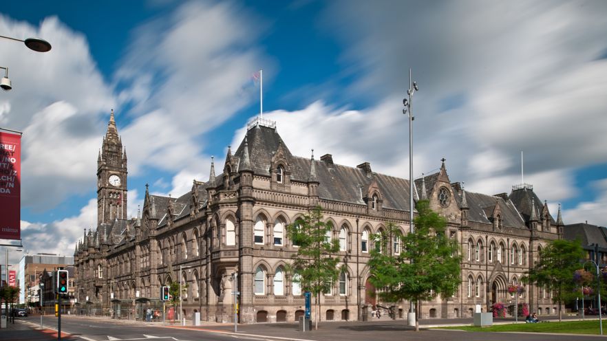 An external picture of Middlesbrough Town Hall, a grand square building, with a grass square and trees nearby