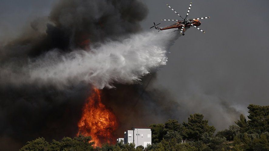 A firefighting helicopter tries to extinguish a wildfire threatening houses at the north-east suburb of Pallini, near Athens, Greece, 20 July 2022.