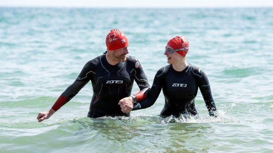 Maria Gorniok, 26, and her dad Julian Gorniok, 57 finished the swim together both can be seen in black wetsuits and red swim caps holding hands as they exit the sea.