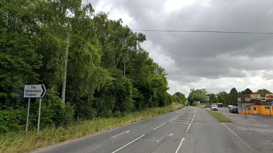 Part of the A30, with a sign to The Winterslows, part of a junction and a business on the side of the road