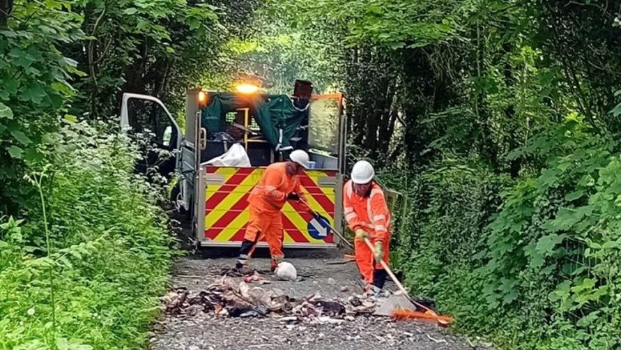 Men clearing waste from a lane