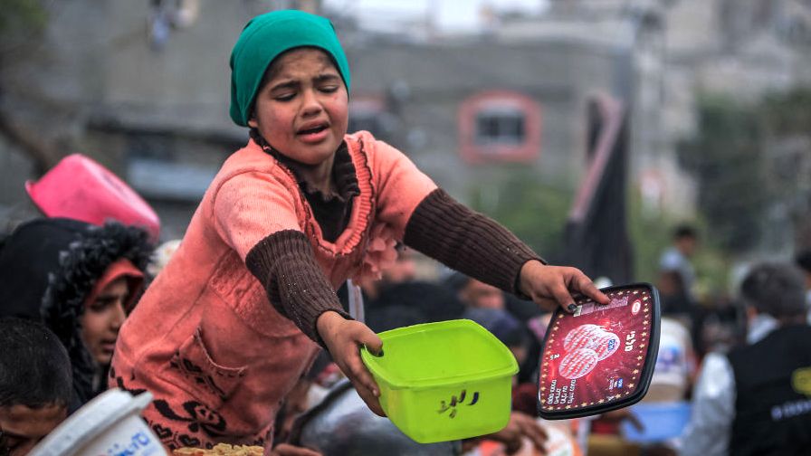 Children queue for food hold buckets