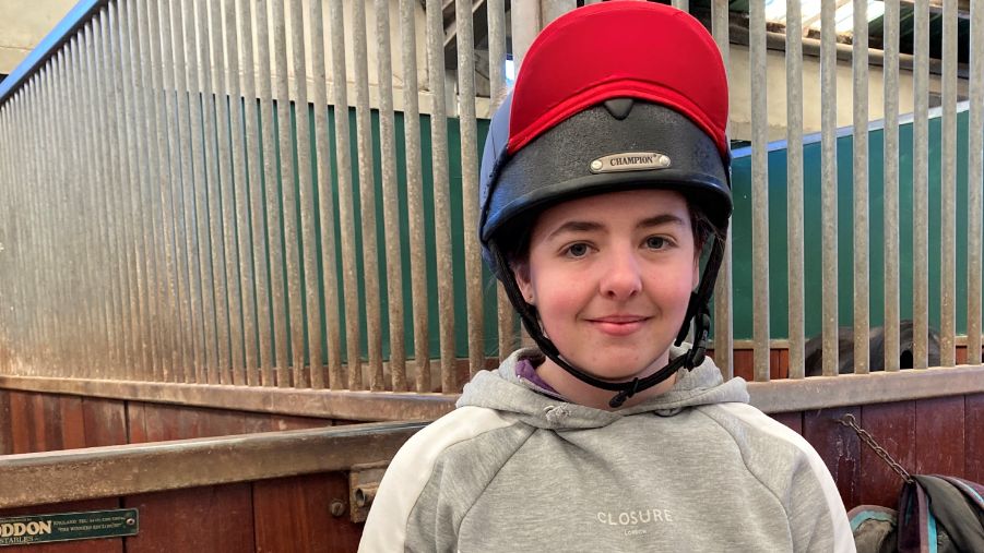 Talia Rayner-Smith in a riding helmet, in front of a stable