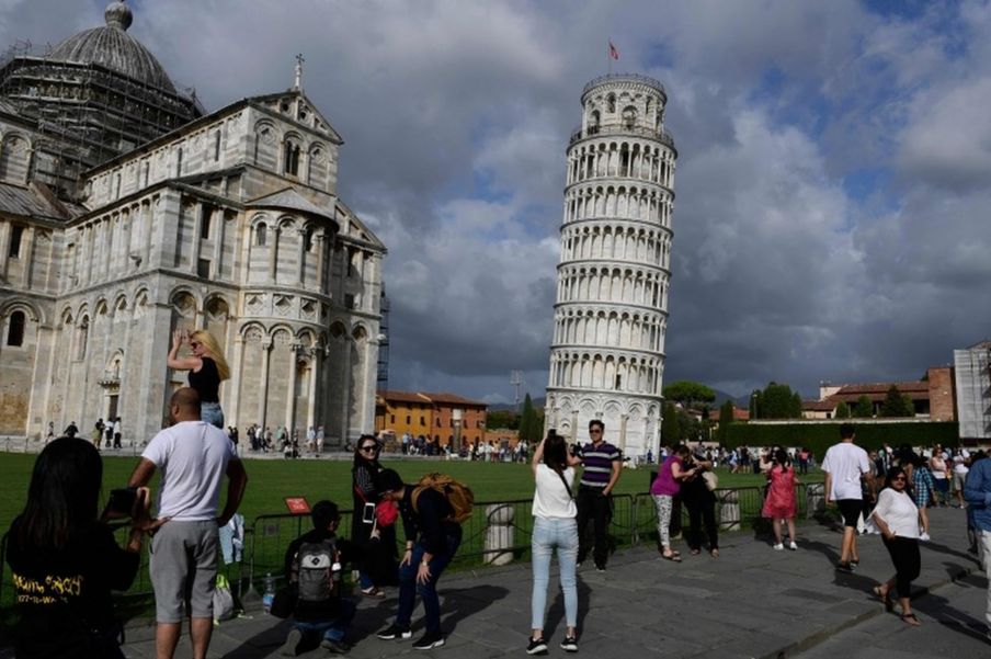 Turistas posam em frente à Torre de Pisa