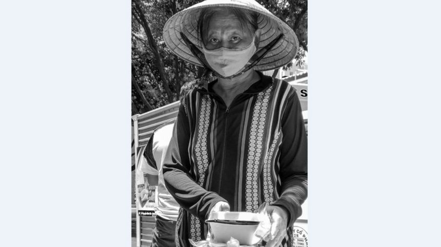 Bà cụ đội nón lá đi kiếm bữa trưa cho mình, lúc 11 giờ trên đường Nguyễn Văn Thủ, Q1