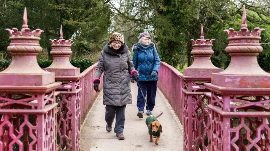 Dog walkers cross an ornate heritage bridge