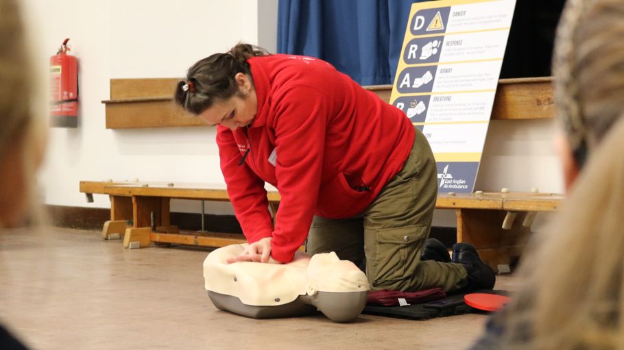 Woman in red fleece doing chest compressions on dummy