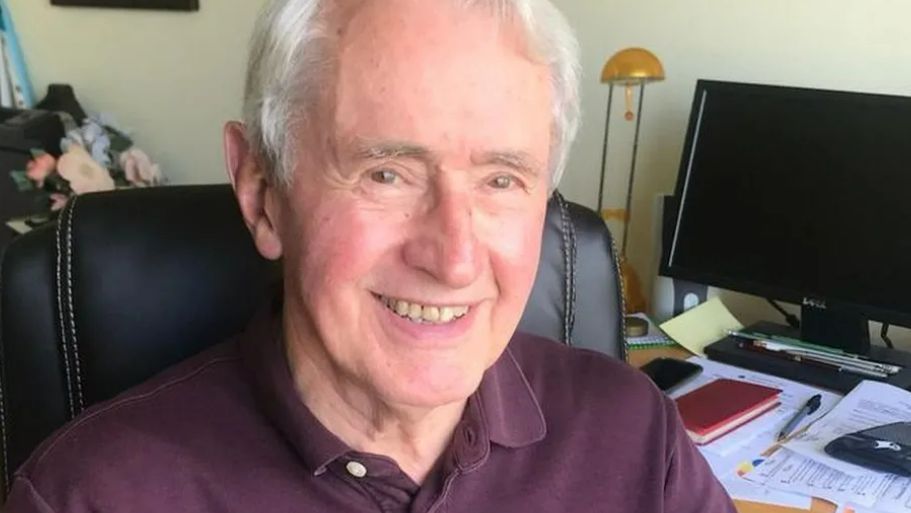 John Codd sitting at a desk, smiling at the camera in a family photo