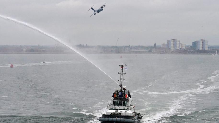 Flypast by an RAF A400 and tugboat spraying water as ferry with veterans left Portsmouth