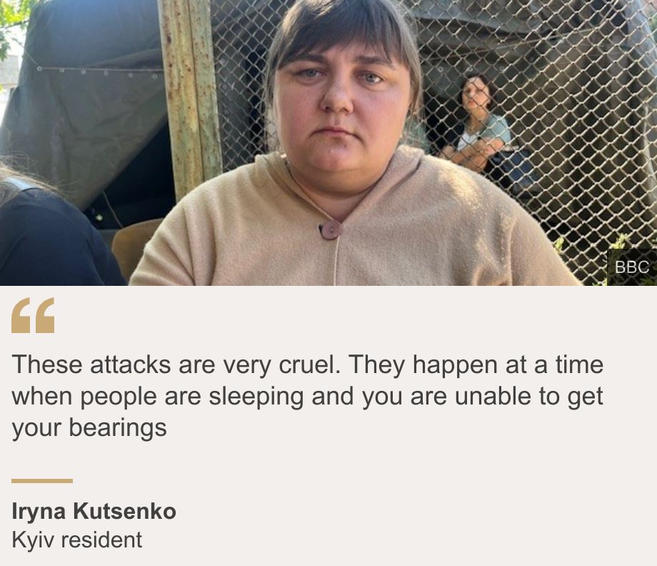 "These attacks are very cruel. They happen at a time when people are sleeping and you are unable to get your bearings", Source: Iryna Kutsenko, Source description: Kyiv resident, Image: A woman called Iryna sits outside unsmiling, waiting to hear news of her mother who is missing after attacks on Kyiv