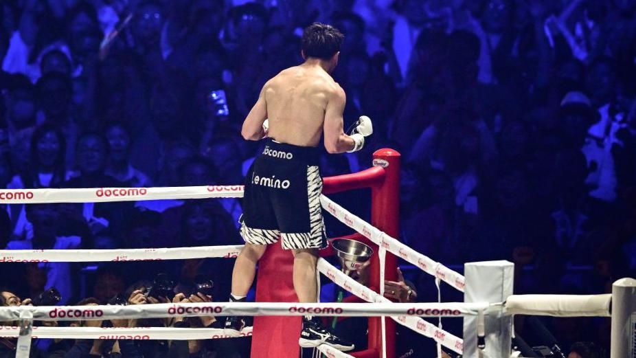 Naoya Inoue stands on the ropes celebrating to the crowd in Japan