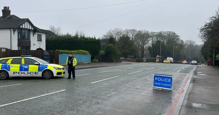 A road with a police cordon in the foreground with other emergency services vehicles visible in the distance