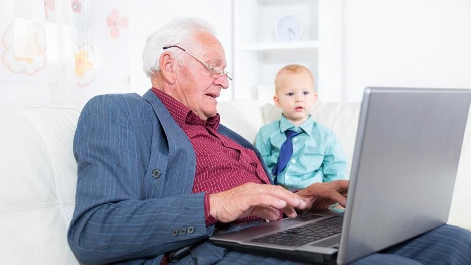 Old man with laptop watched by baby