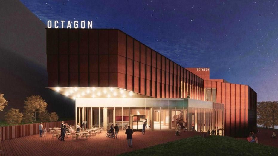 Artist's impression of an upgraded Octagon Theatre in Yeovil. It shows a large building, with a glass front. It has been lit up at night and looks red in colour. There are people walking outside and tables and chairs near the entrance. The word 'Octagon' is prominently displayed on the roof.