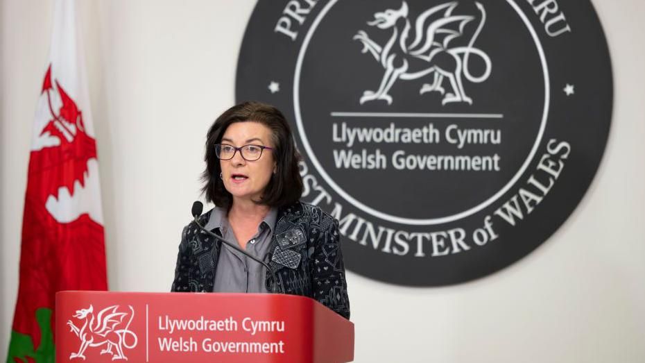 Eluned Morgan standing at a Welsh government podium