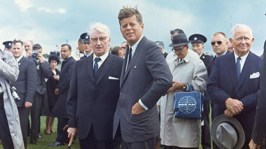 A group of people standing in a field wearing suits