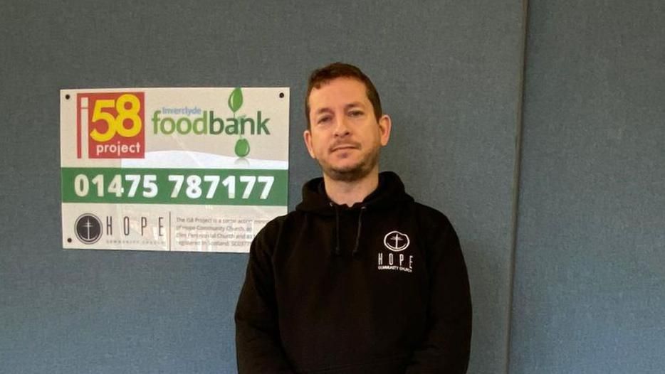 Adam Wines with a food bank sign 