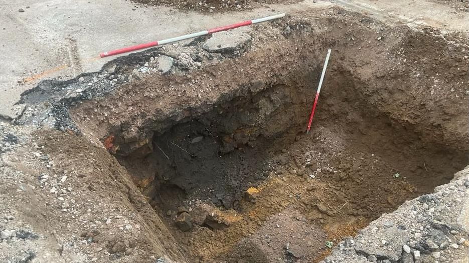 Deep archaeology trench showing distance poles