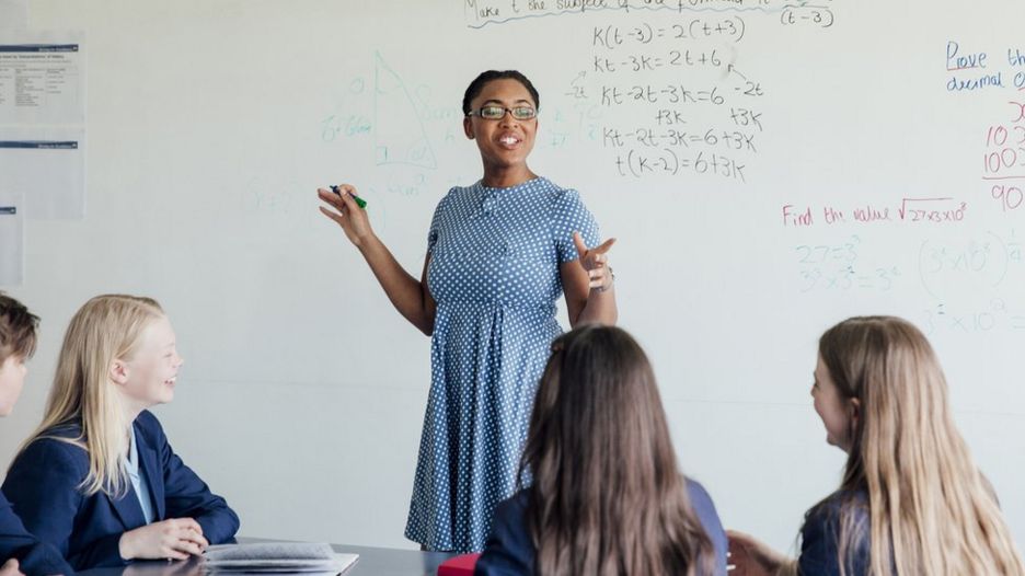 Professora ensinando fÃ³rmulas em uma classe